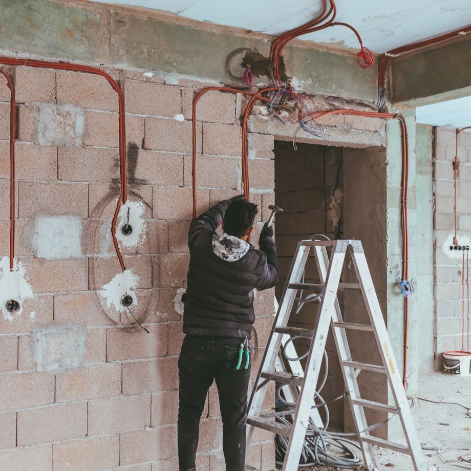 Illustrative licensed photograph: Electrician installing wiring during a building renovation