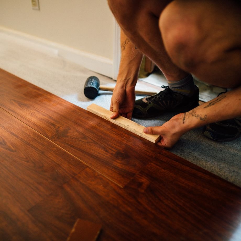 Illustrative licensed photograph: Craftsman installing laminate wood floor