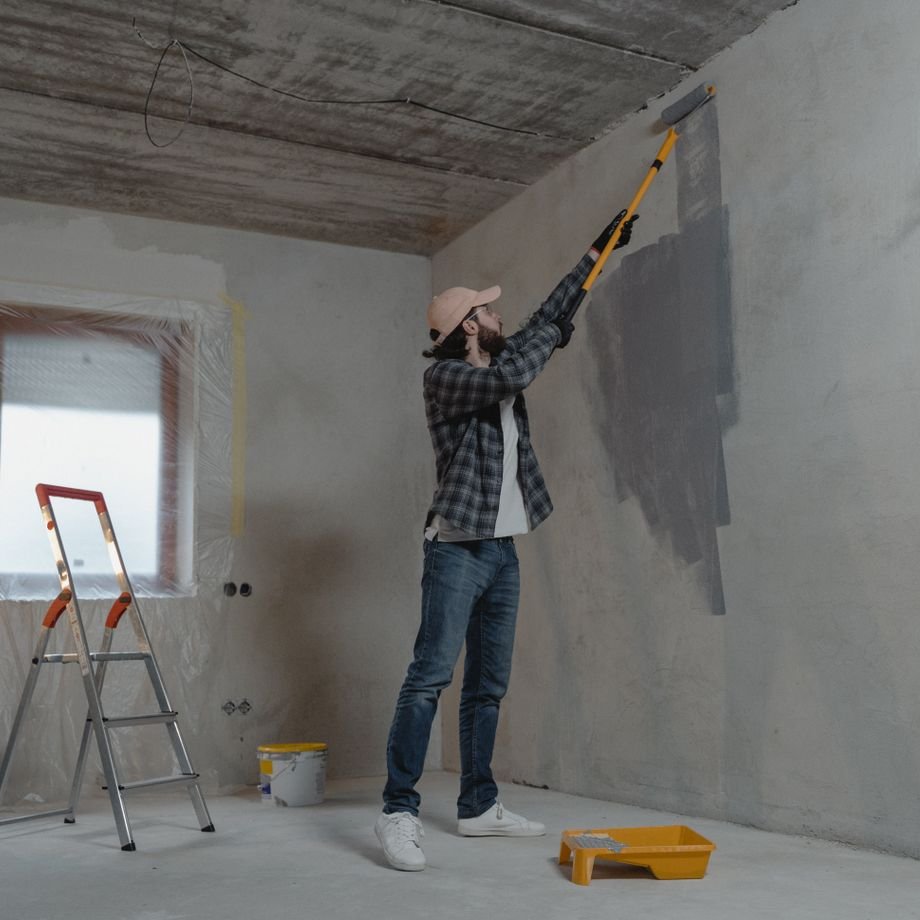 Illustrative licensed photograph: Professional painting a wall inside a residential property