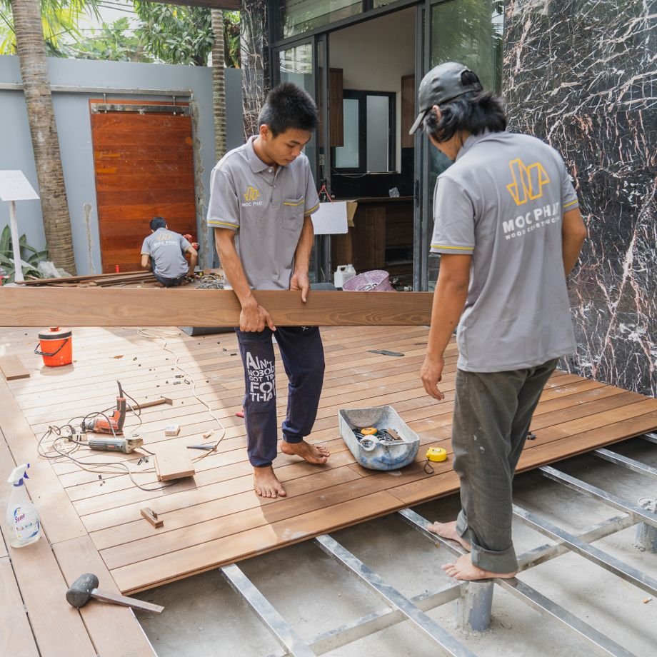 Illustrative licensed photograph: Wood flooring contractors installing decking