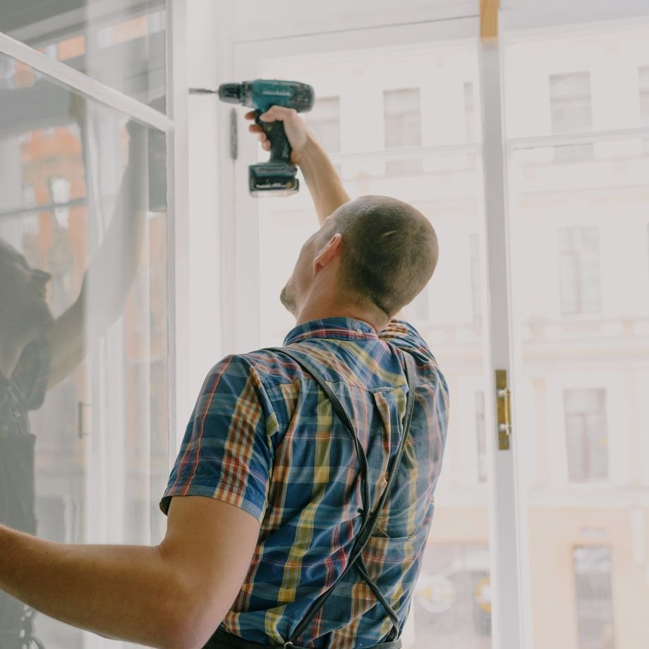 Illustrative licensed photograph: Handyman installing a window frame in a residence