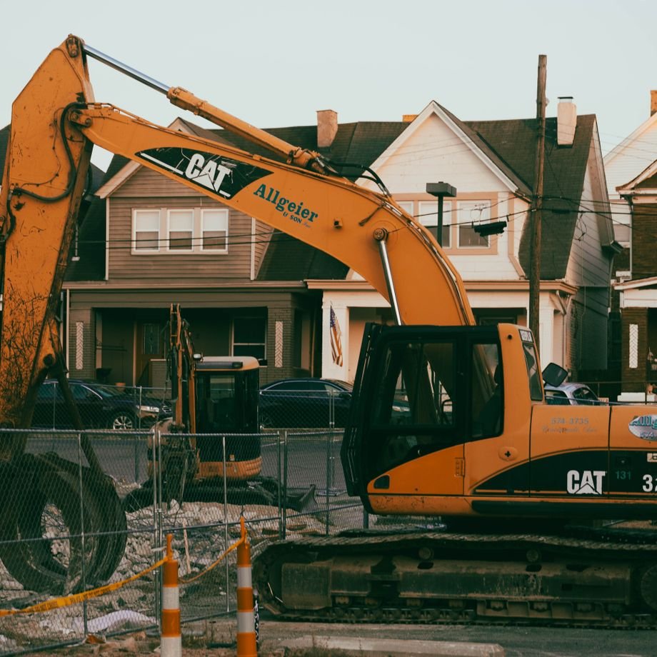 Illustrative licensed photograph: Excavator operating in a suburban residential neighborhood