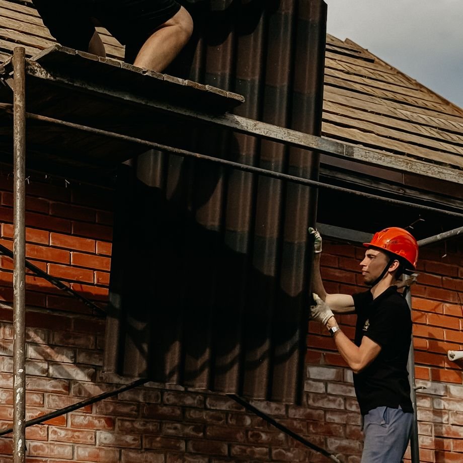 Illustrative licensed photograph: Roof panel installation on residential scaffolding