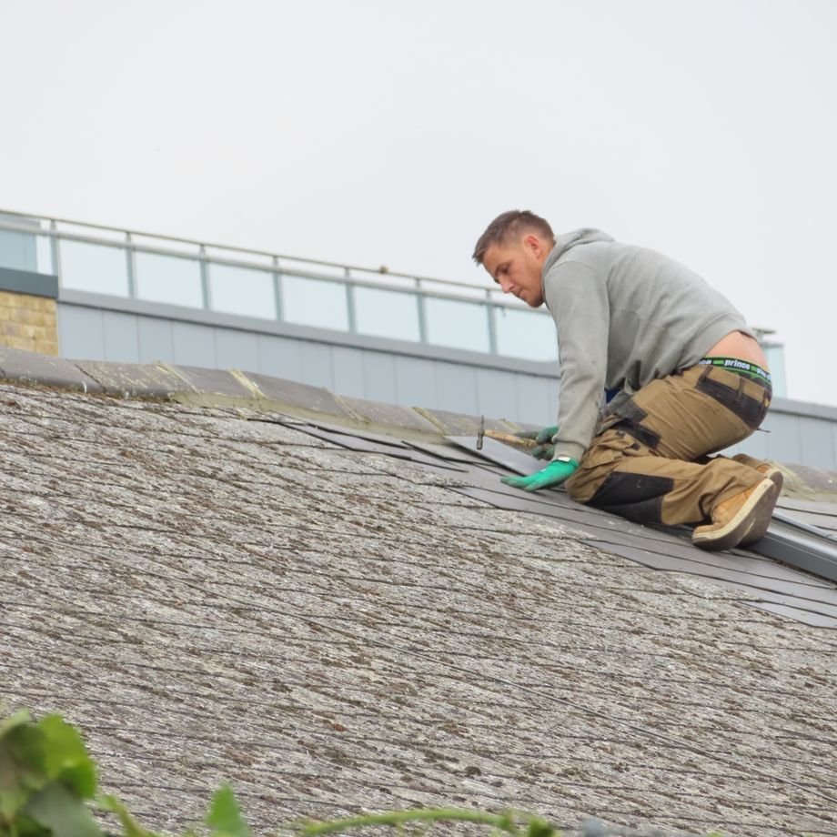 Illustrative licensed photograph: Roofer placing tiles on residential roof
