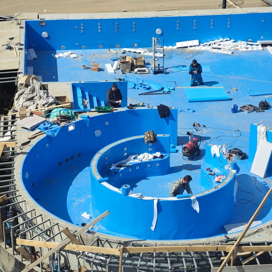 Illustrative licensed photograph: Pool builders constructing a swimming pool