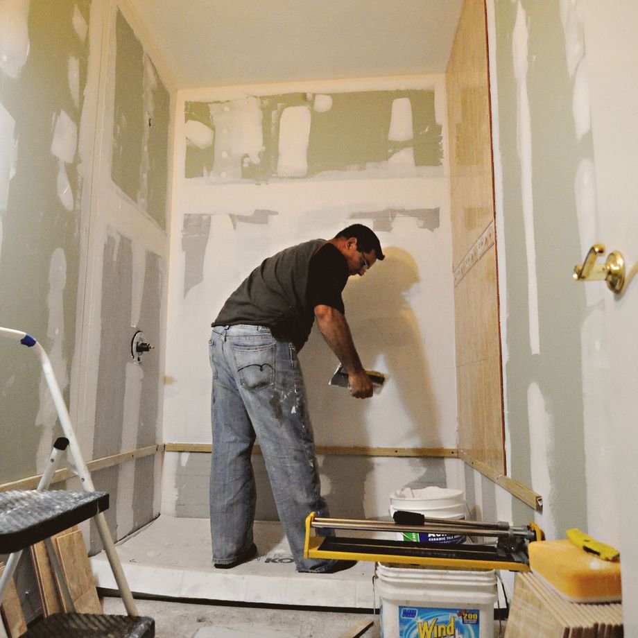Illustrative licensed photograph: Worker carrying out interior bathroom drywall renovation